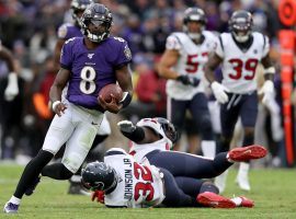 Baltimore Ravens Quarterback Lamar Jackson evades tacklers from the Houston Texans. (Tommy Gilligan/USA Today Sports)