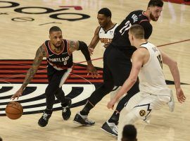 Damian Lillard of the Portland Trail Blazers splits a pair of Denver nuggets defenders, including Nikola Jokic, on a pick-and-roll in Game 4 at the Moda Center in Portland. (Image: Denver Post)